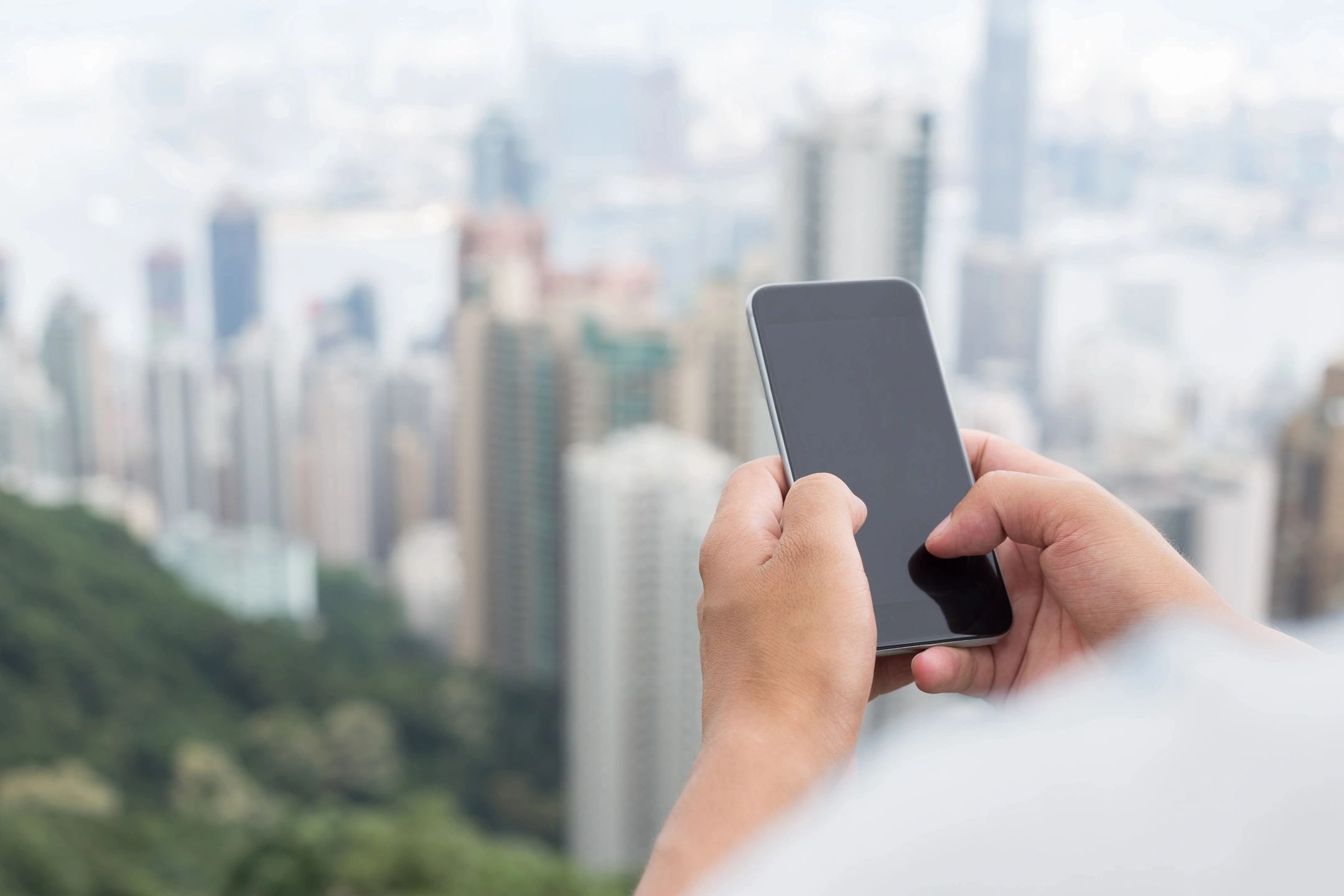 Hands holding a cellphone overlooking city